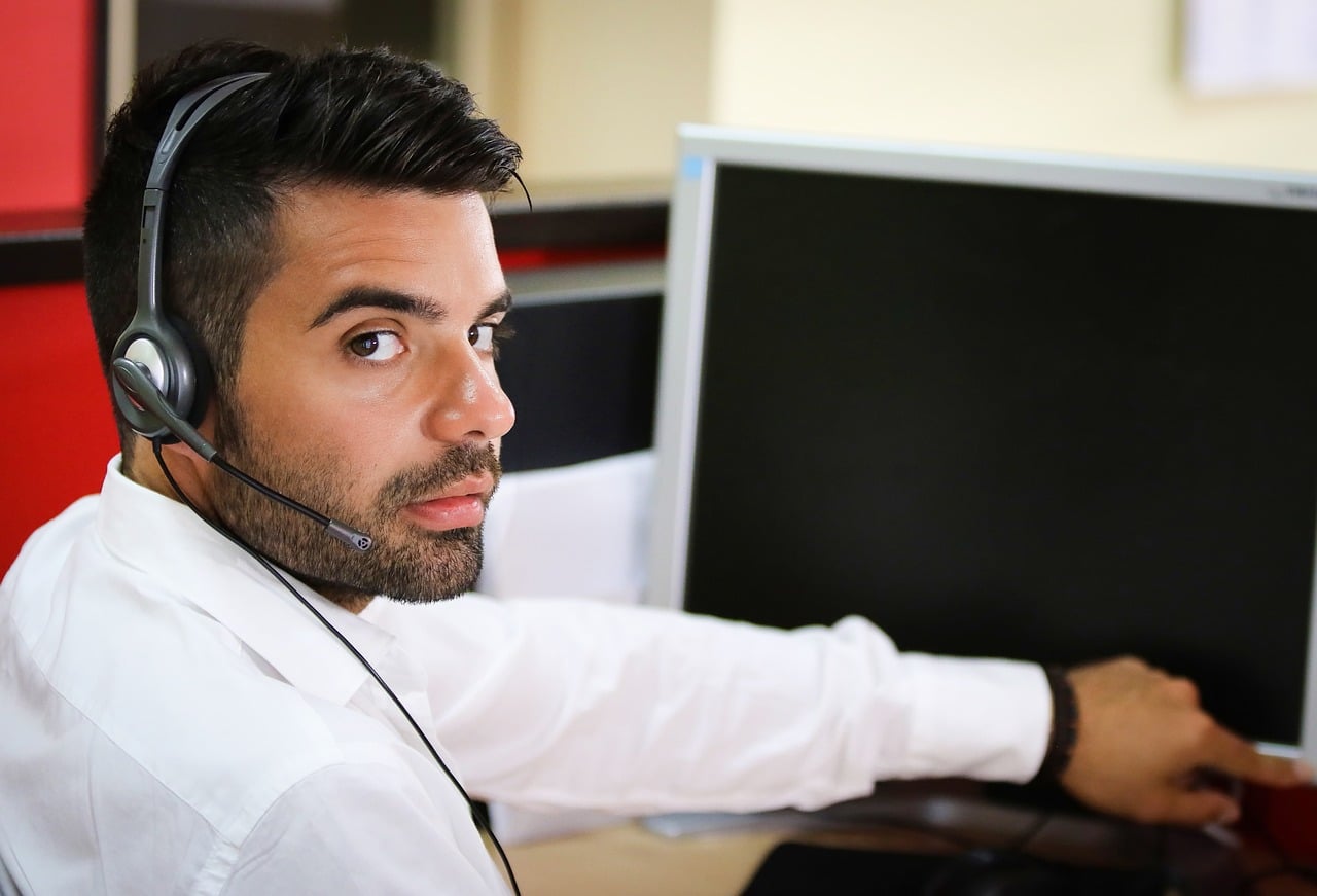 Operatore di call center con cuffie e microfono davanti al monitor, rappresentazione professionale dell'assistenza clienti tramite software cloud per contact center.