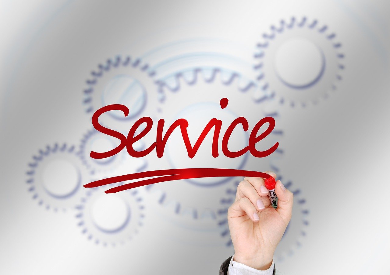 Mano che scrive la parola "Service" in rosso su sfondo con ingranaggi, concetto di customer service e automazione aziendale.
